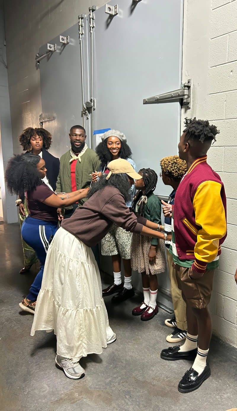 Stylists make final adjustments to participants' outfits backstage before a shoot
