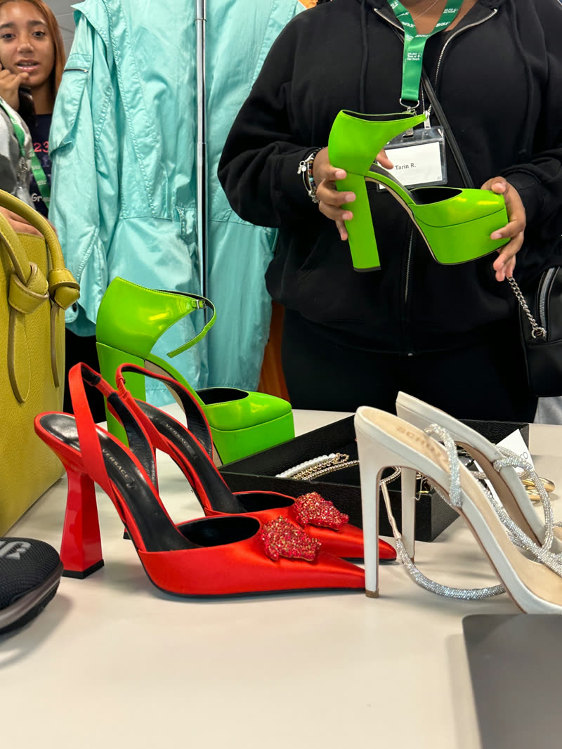 Participants examine designer footwear arranged on a styling table during a workshop